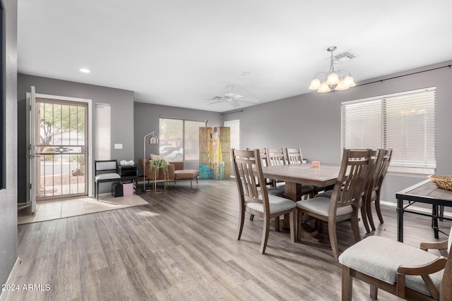 dining area with ceiling fan with notable chandelier and light hardwood / wood-style floors