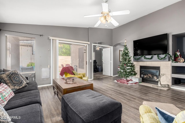 living room featuring a tile fireplace, ceiling fan, wood-type flooring, and lofted ceiling