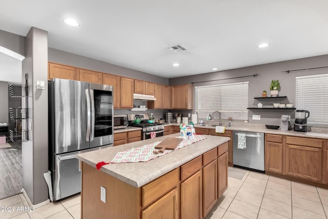 kitchen featuring a center island, light tile patterned flooring, sink, and appliances with stainless steel finishes