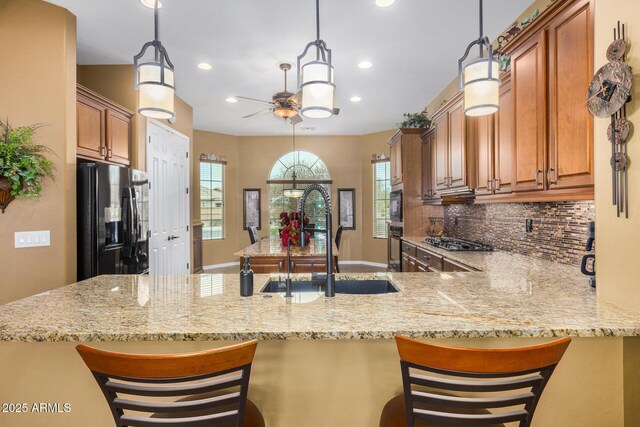 kitchen featuring black appliances, a breakfast bar, kitchen peninsula, and sink