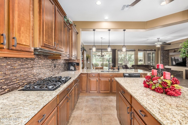 kitchen with sink, backsplash, ornamental molding, stainless steel gas cooktop, and light stone counters