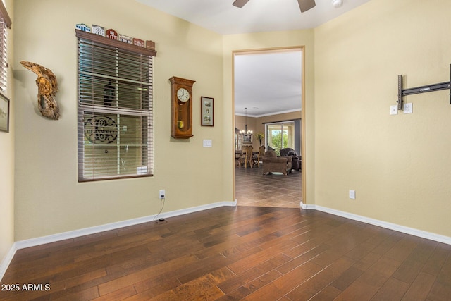 empty room featuring crown molding, dark hardwood / wood-style flooring, and ceiling fan with notable chandelier