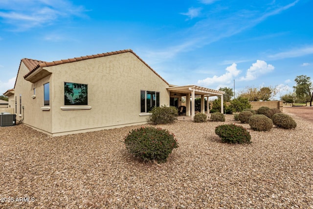 rear view of house featuring central AC unit, a pergola, and a patio area