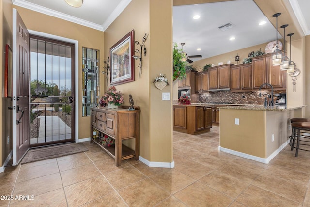 entryway with ceiling fan, light tile patterned flooring, and ornamental molding