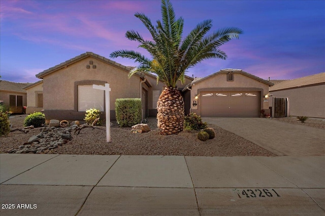 view of front of house with a tile roof, a garage, driveway, and stucco siding