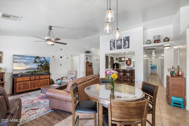 dining space featuring a ceiling fan, light tile patterned floors, lofted ceiling, and visible vents