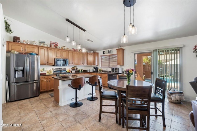 kitchen with vaulted ceiling, appliances with stainless steel finishes, a center island, visible vents, and dark countertops