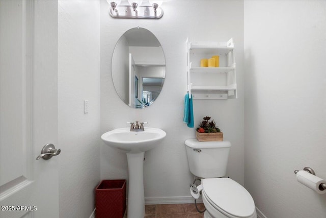 bathroom featuring a sink, baseboards, toilet, and tile patterned flooring