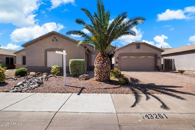 view of front of home featuring decorative driveway, a tile roof, stucco siding, and an attached garage