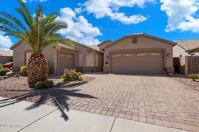 ranch-style house with stucco siding, a tile roof, a garage, and decorative driveway