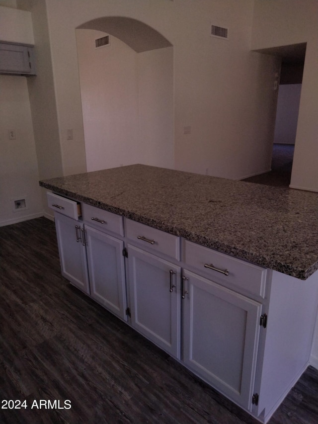 kitchen featuring white cabinets, dark stone countertops, and dark wood-type flooring