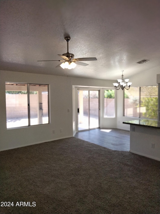 unfurnished living room featuring ceiling fan with notable chandelier, carpet floors, and a textured ceiling