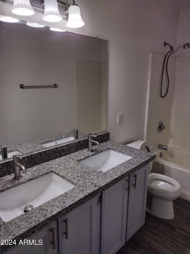 full bathroom with vanity, hardwood / wood-style floors, washtub / shower combination, and toilet