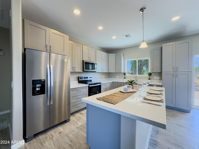 kitchen with gray cabinets, a center island, stainless steel appliances, and decorative light fixtures