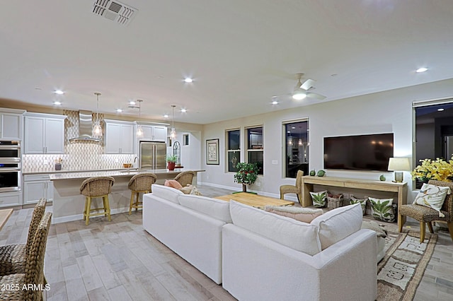 living area with visible vents, baseboards, light wood-style flooring, ceiling fan, and recessed lighting