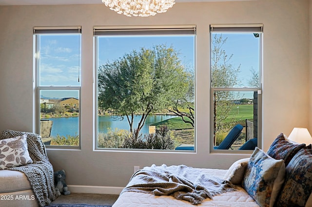 carpeted bedroom with a chandelier, a water view, and baseboards