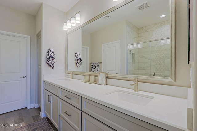bathroom with double vanity, a stall shower, a sink, and visible vents