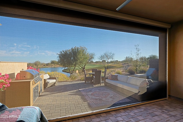 view of patio / terrace featuring exterior kitchen, a water view, and area for grilling
