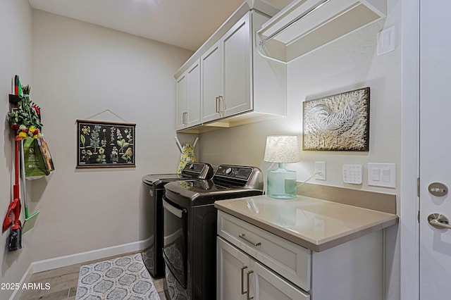 washroom featuring cabinet space, washer and clothes dryer, baseboards, and light wood finished floors
