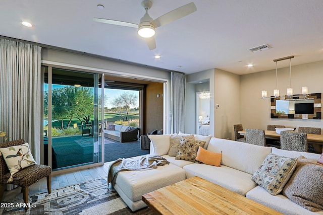 living room with recessed lighting, visible vents, wood finished floors, and ceiling fan with notable chandelier