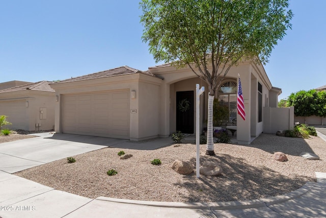 view of front facade with stucco siding, an attached garage, driveway, and a tiled roof