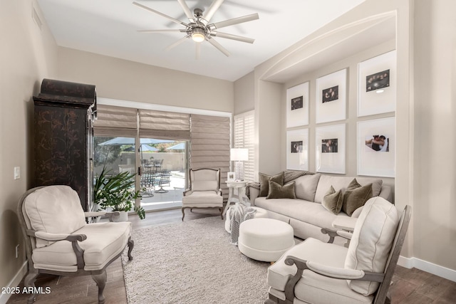 living area featuring a ceiling fan, baseboards, visible vents, and wood finished floors