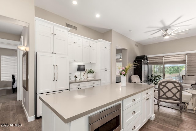 kitchen with ceiling fan, built in appliances, a center island, white cabinetry, and visible vents