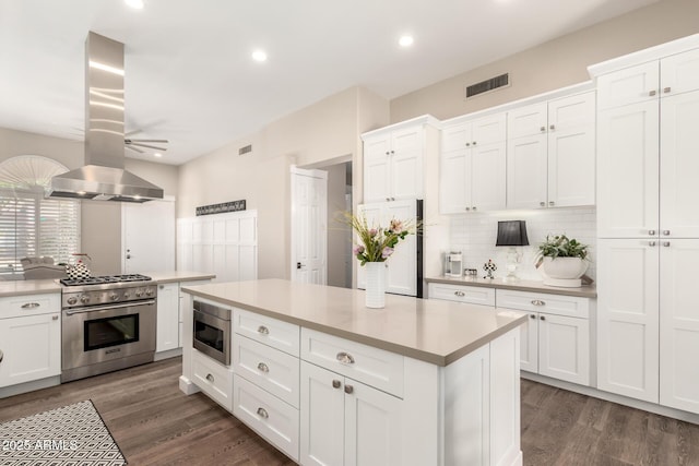 kitchen featuring appliances with stainless steel finishes, light countertops, decorative backsplash, island exhaust hood, and visible vents