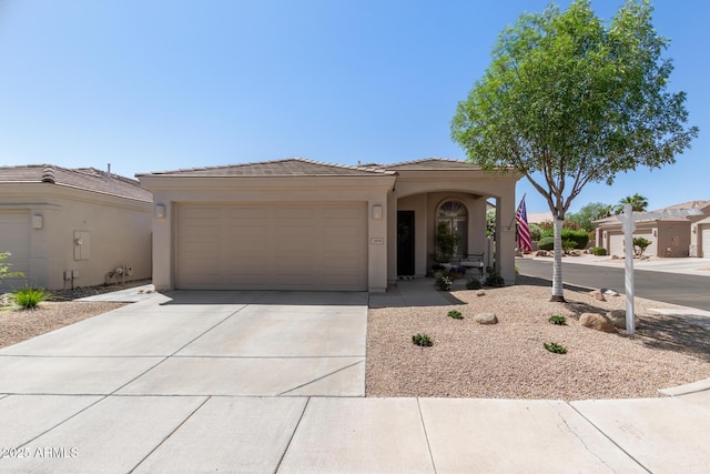 view of front facade with a garage, driveway, a tile roof, and stucco siding