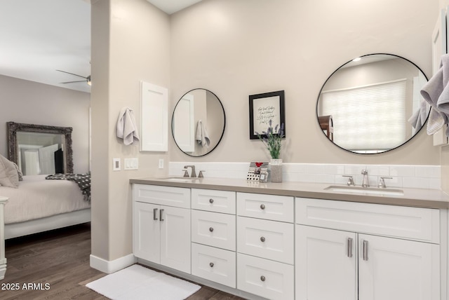 ensuite bathroom featuring double vanity, a sink, and wood finished floors
