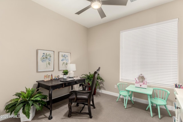 carpeted office space with a ceiling fan and baseboards
