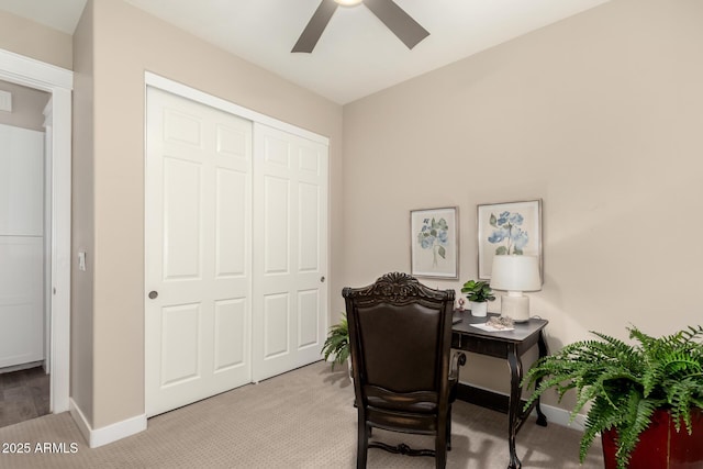 home office featuring baseboards, a ceiling fan, and light carpet