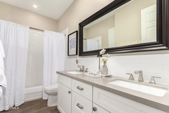 full bathroom with a sink, wood finished floors, shower / tub combo with curtain, and toilet