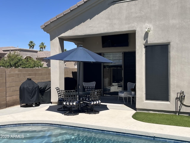 rear view of property with fence, a fenced in pool, a patio, and stucco siding
