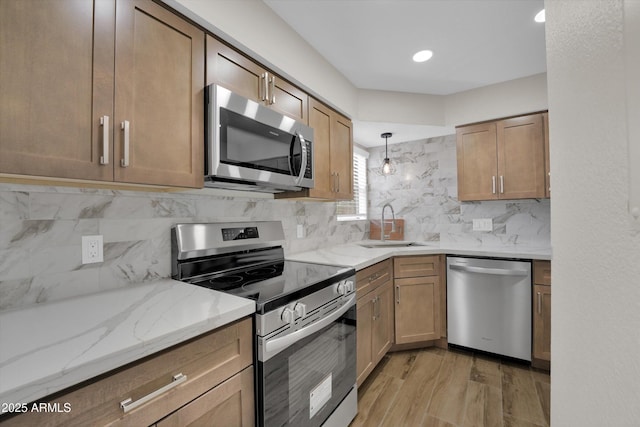 kitchen with pendant lighting, sink, tasteful backsplash, and appliances with stainless steel finishes