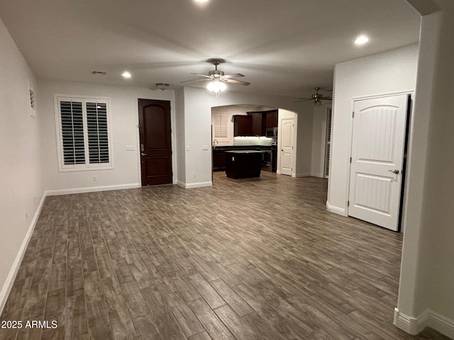 unfurnished living room featuring dark hardwood / wood-style floors and ceiling fan