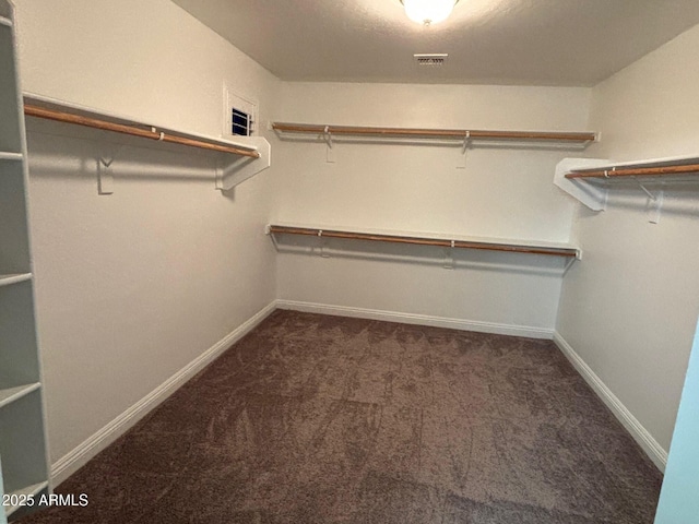 walk in closet featuring dark carpet