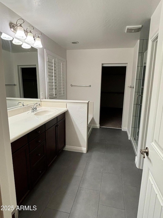 bathroom featuring vanity, a shower with shower door, tile patterned flooring, and a textured ceiling