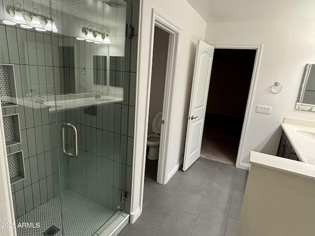 bathroom featuring tile patterned floors, vanity, toilet, and a shower with shower door