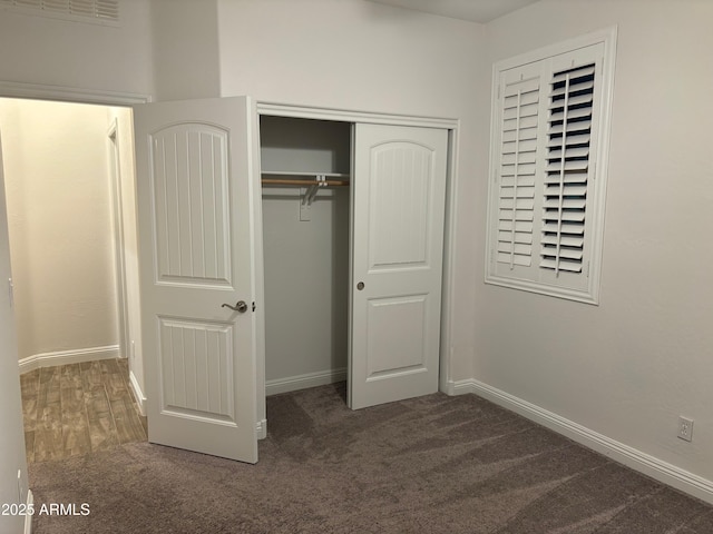 unfurnished bedroom featuring a closet and dark colored carpet