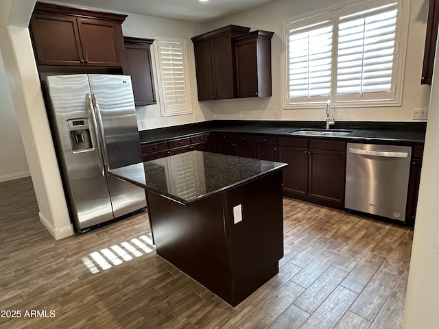 kitchen with sink, a center island, light hardwood / wood-style flooring, dark stone countertops, and stainless steel appliances