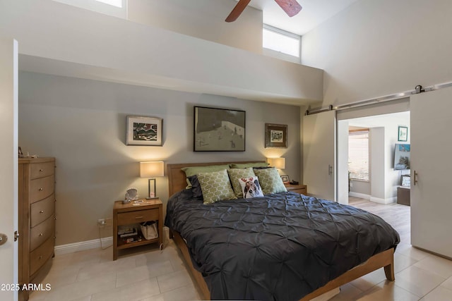 bedroom with tile patterned floors, a towering ceiling, baseboards, and a barn door