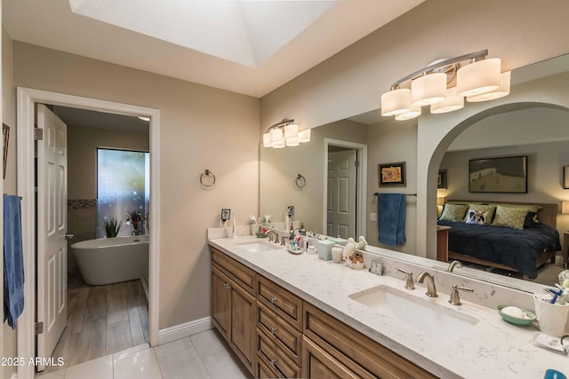 bathroom with a freestanding bath, double vanity, a sink, and connected bathroom