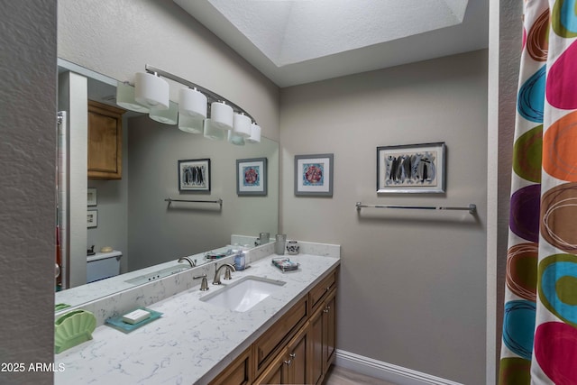 bathroom with toilet, vanity, and baseboards