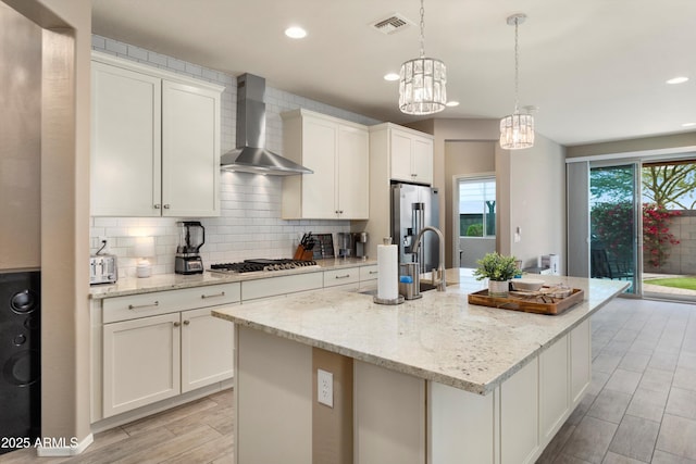 26242 N 122nd Ln, Peoria, AZ 85383 - kitchen with tasteful backsplash, wall chimney range hood, white cabinetry, appliances with stainless steel finishes, and a center island with sink