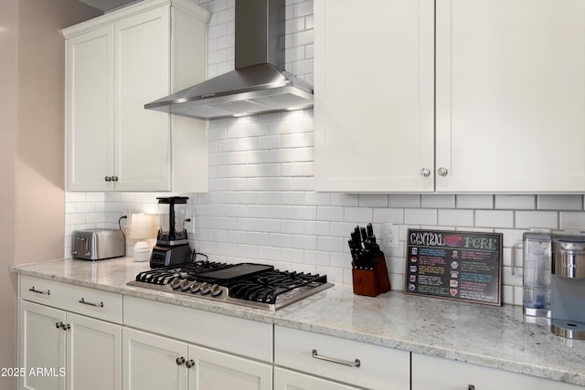 26242 N 122nd Ln, Peoria, AZ 85383 - kitchen featuring light stone counters, wall chimney range hood, white cabinets, stainless steel gas cooktop, and decorative backsplash