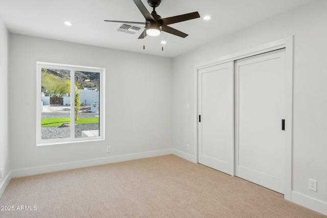 unfurnished bedroom featuring ceiling fan, light colored carpet, and a closet