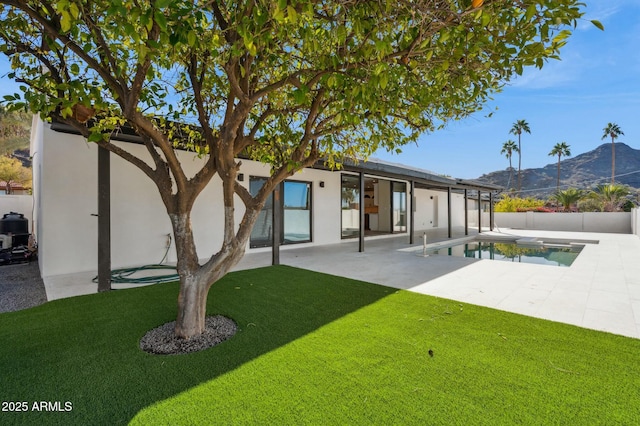 rear view of house with a fenced in pool, a patio, a yard, and a mountain view