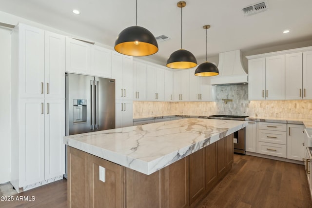 kitchen featuring white cabinets, stainless steel appliances, a center island, and premium range hood