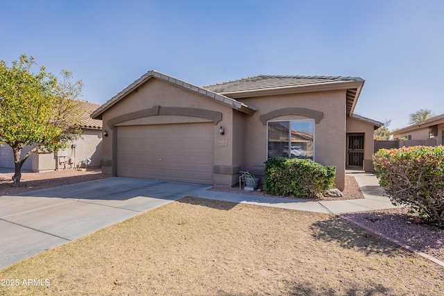 single story home featuring a garage, driveway, a tiled roof, and stucco siding